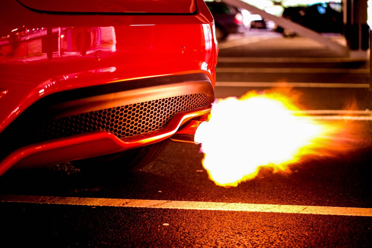 A red car blowing flame from the exhaust pipe
