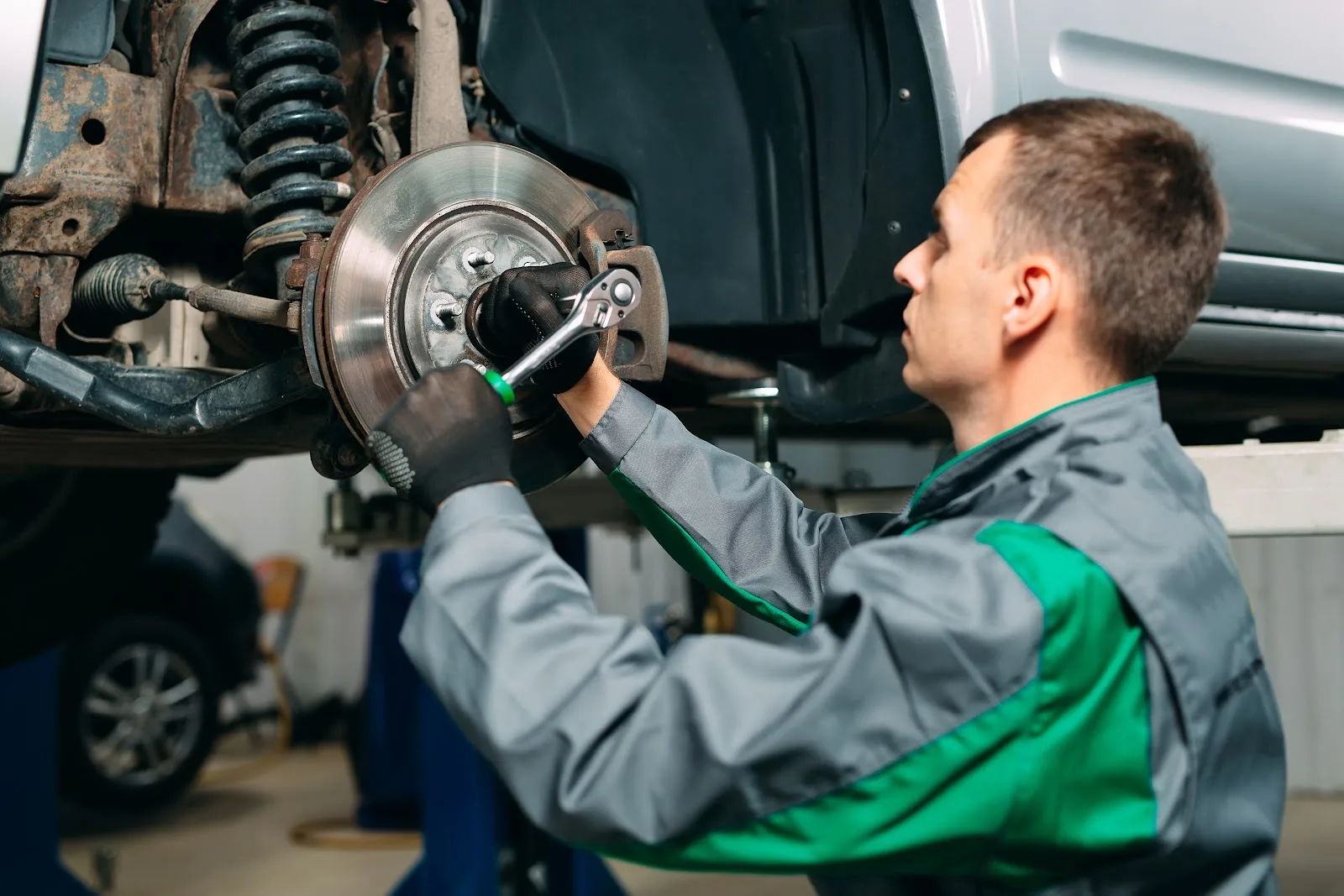 A mechanic inspecting a Toyota Tacoma before beginning the lifting process